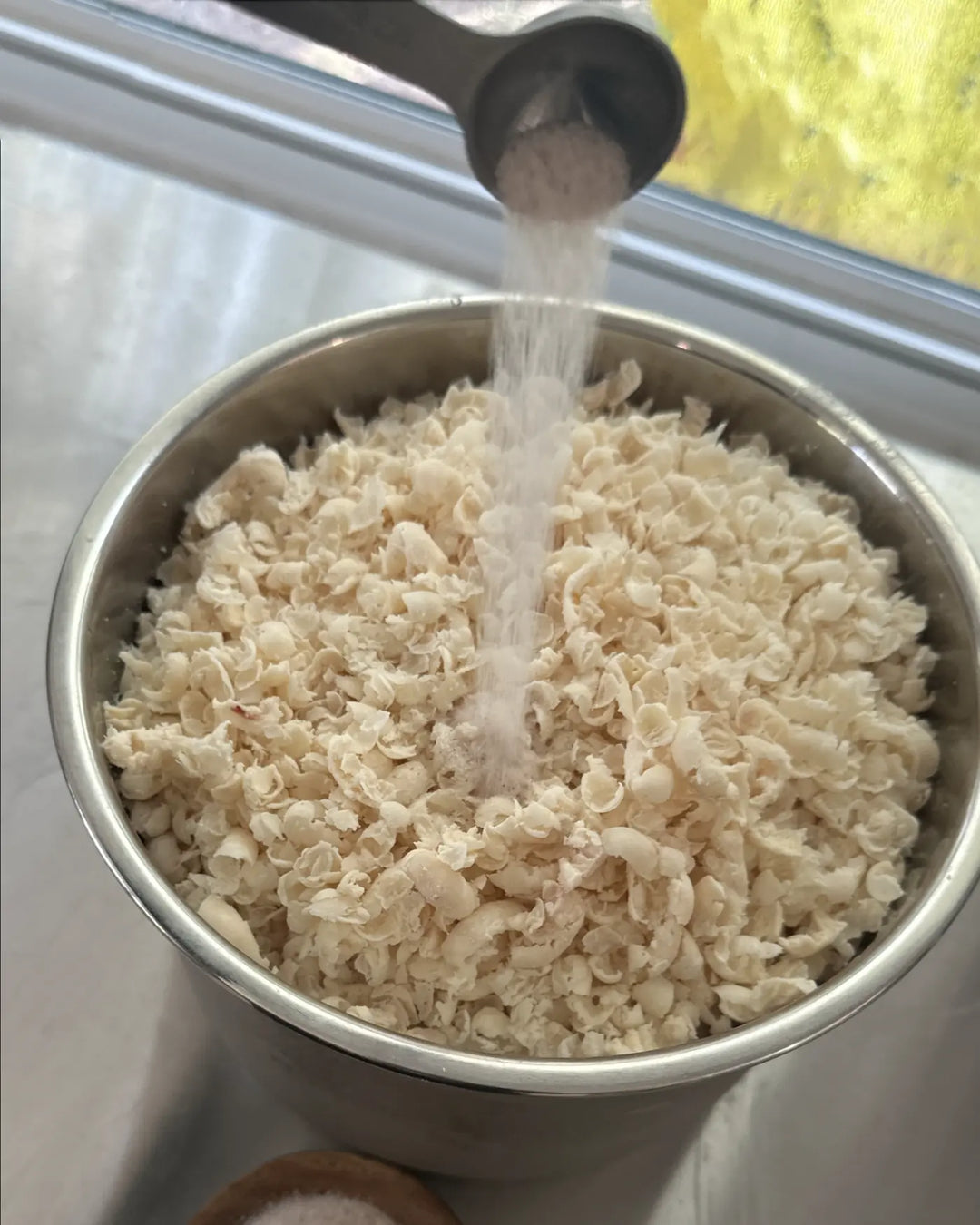 Ancient sea salt being measured and added to fresh whipped tallow curls