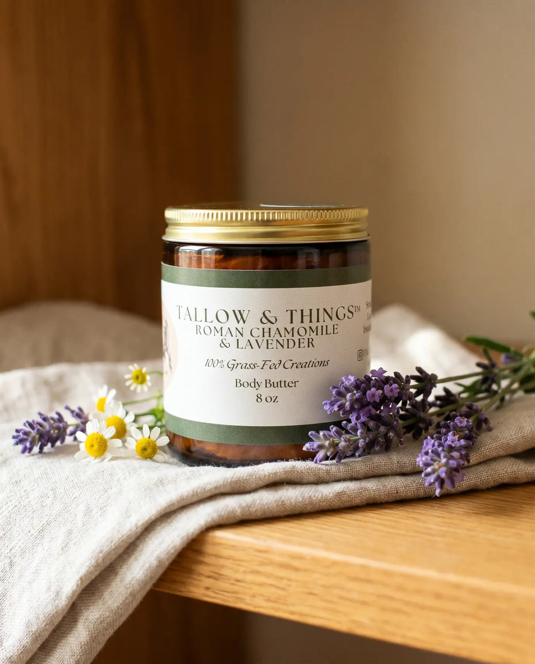Closed 8oz jar of Tallow & Things Roman chamomile and lavender body butter on linen with lavender and chamomile.