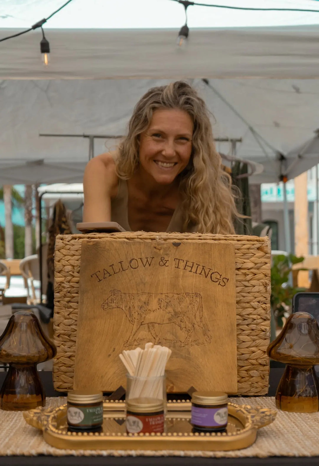 Tallow & Things farmers market booth with the branded wood sign and product jars on display