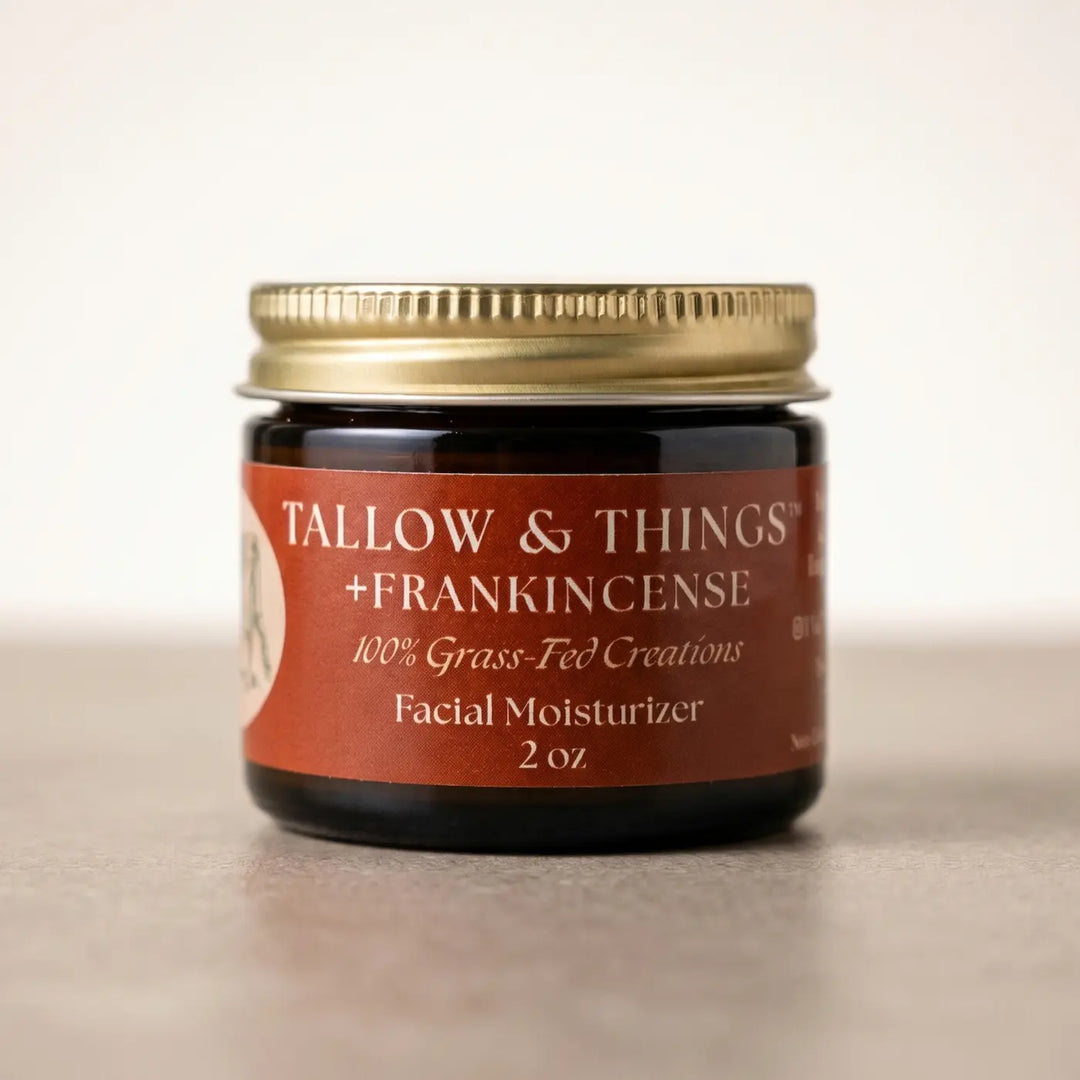 Frankincense tallow facial moisturizer 2oz jar, front label, on a clean warm neutral background.