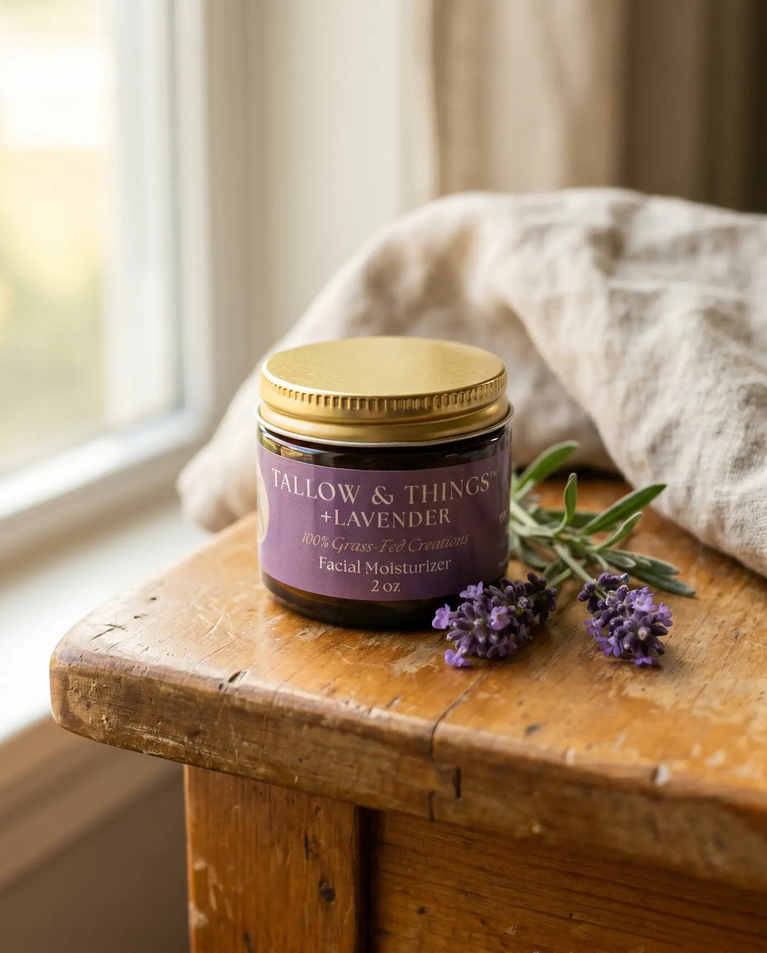 Lavender facial moisturizer jar with fresh lavender sprigs on a wood table in soft window light.