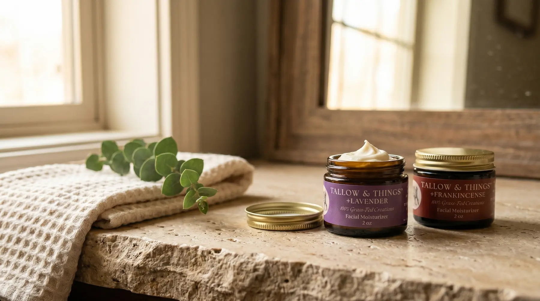 Tallow & Things Lavender and Frankincense balms on a stone bathroom vanity with eucalyptus