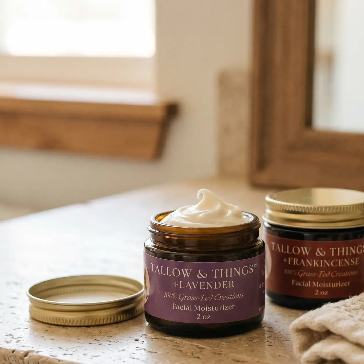 Open jar of Tallow & Things Lavender whipped tallow showing its swirled texture and a frankincense tallow on a vanity