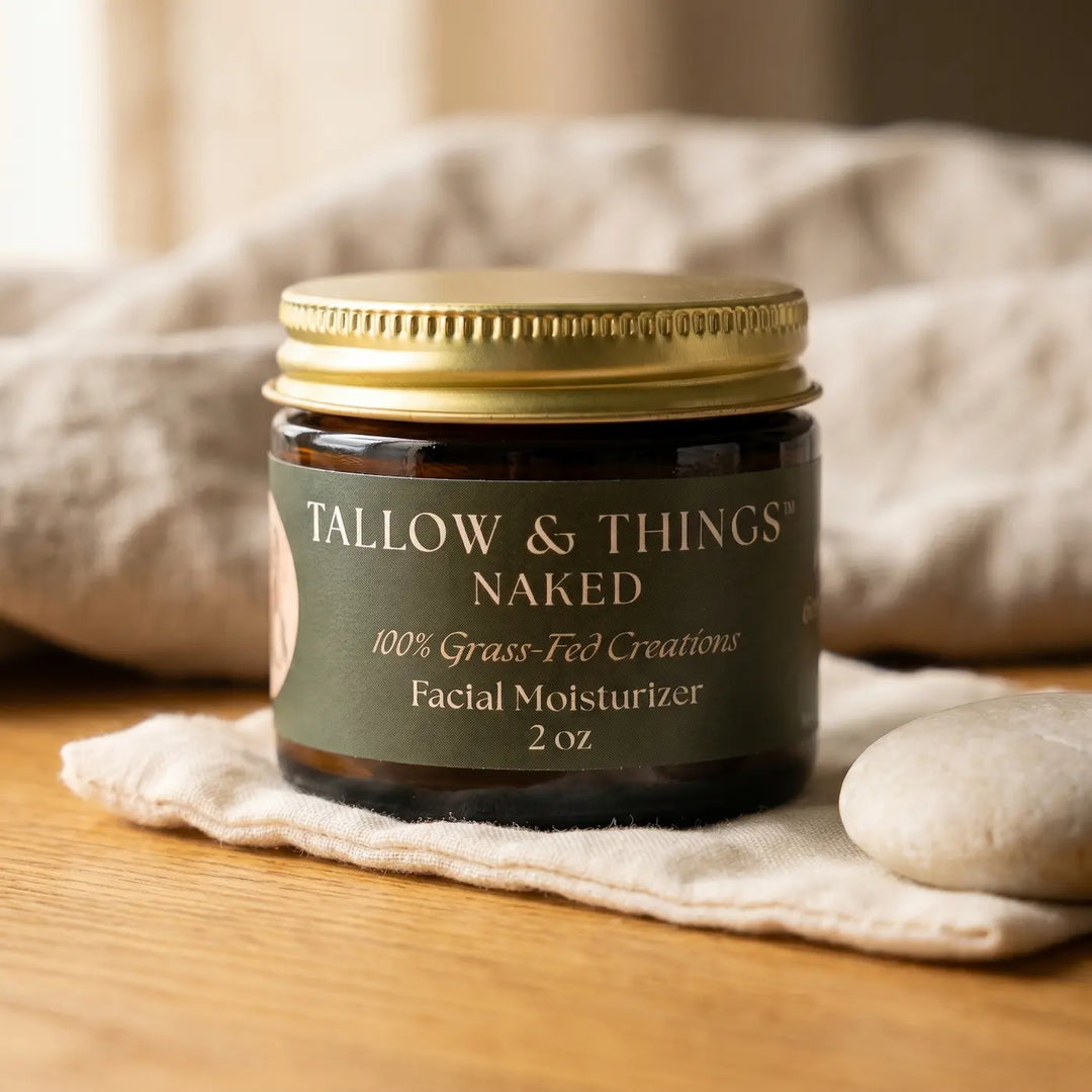 Naked tallow facial moisturizer 2oz jar on oak wood with soft muslin and a smooth stone.