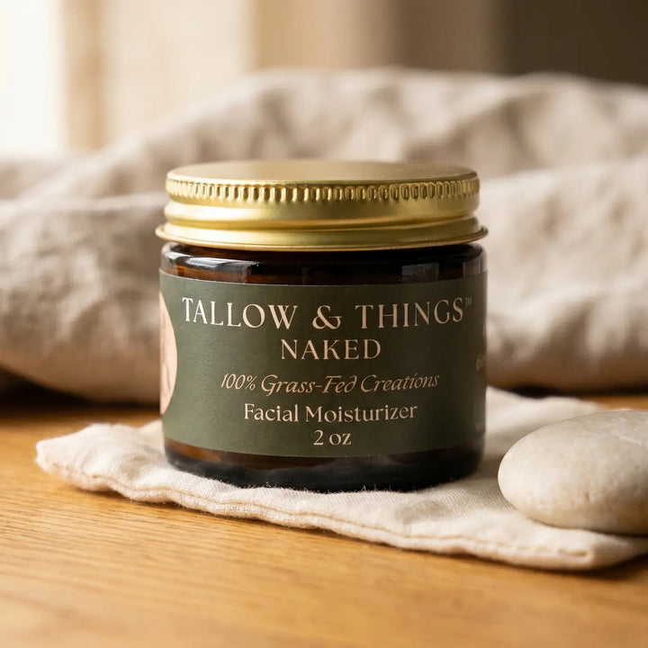 Naked tallow facial moisturizer 2oz jar on oak wood with soft muslin and a smooth stone.