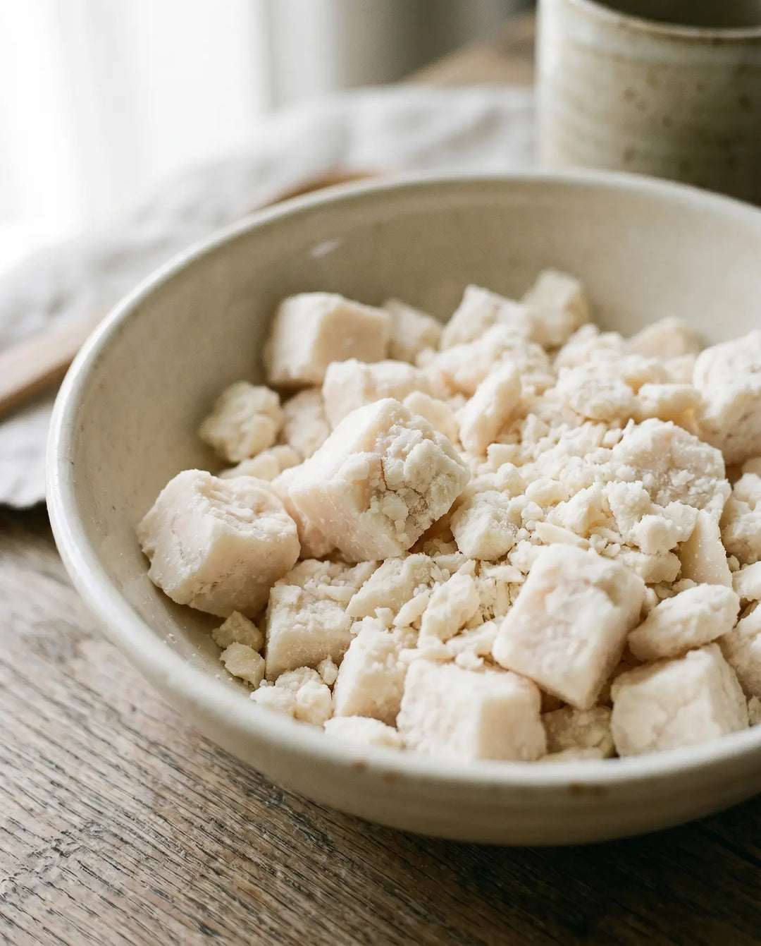 Chunks of rendered grass-fed tallow in a rustic stoneware bowl