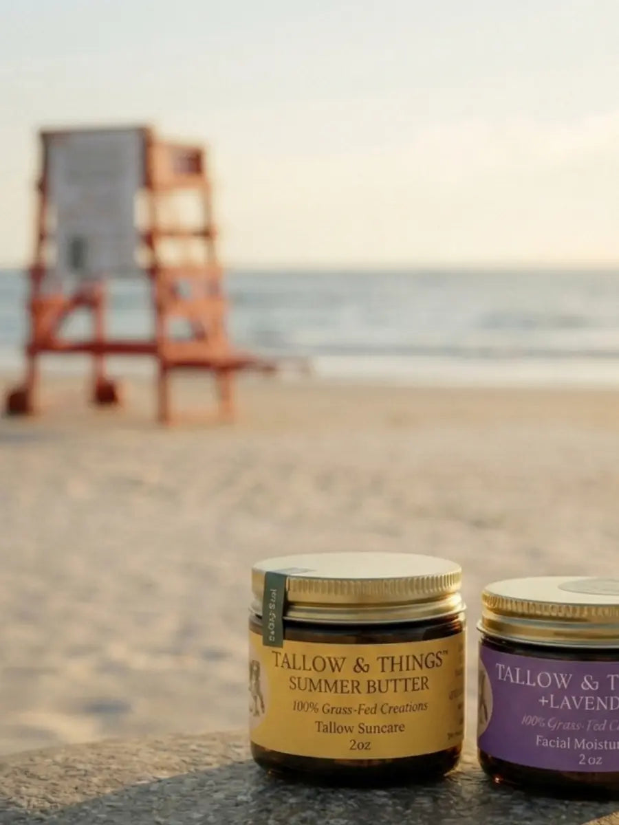 Tallow & Things Summer Butter and Lavender jars on a stone ledge at the beach with a lifeguard stand